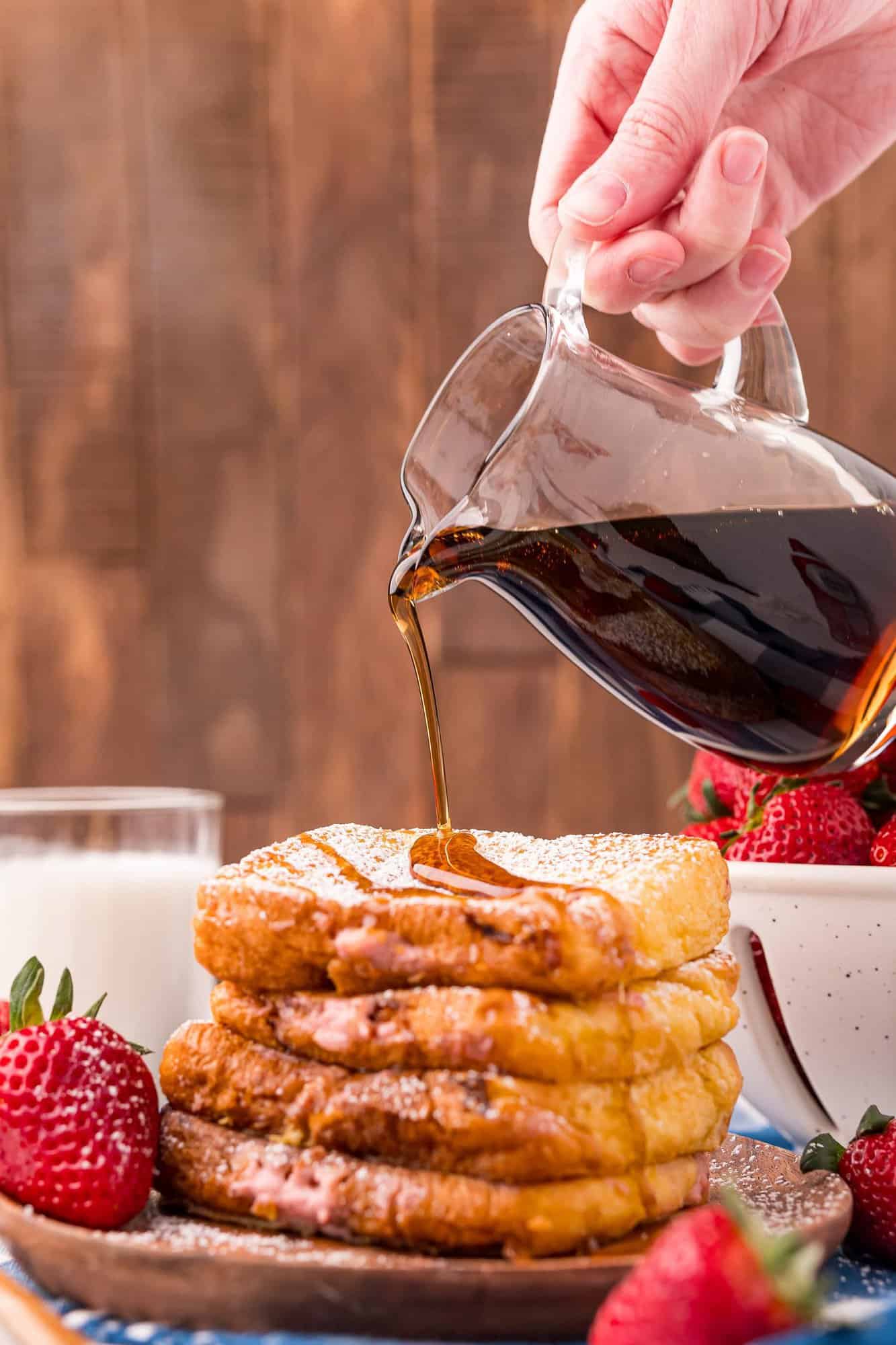 Syrup being poured on a stack of stuffed french toast.