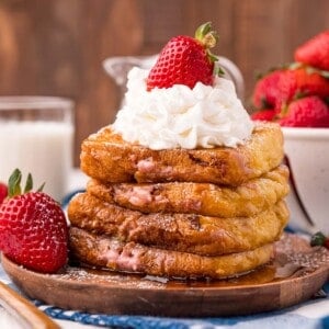 Stack of stuffed french toast, topped with whipped cream and a strawberry.