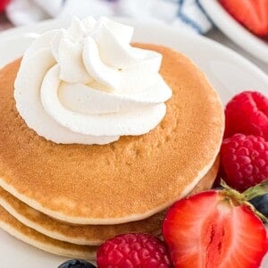 Whipped cream piped onto a small stack of pancakes.