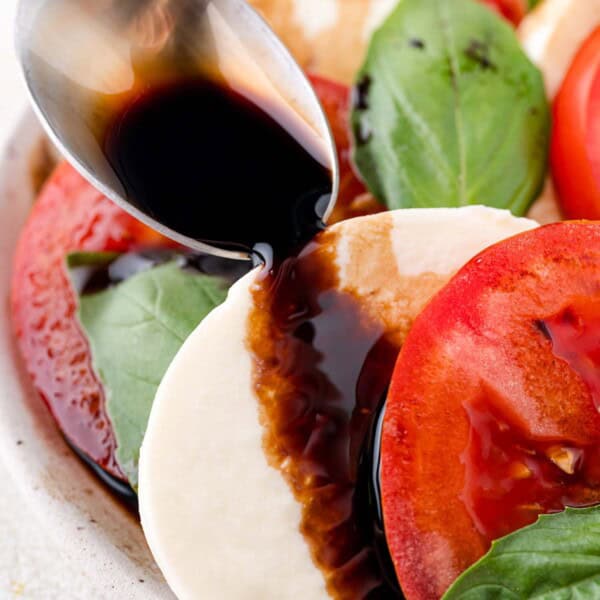 Balsamic glaze being added to a caprese salad.