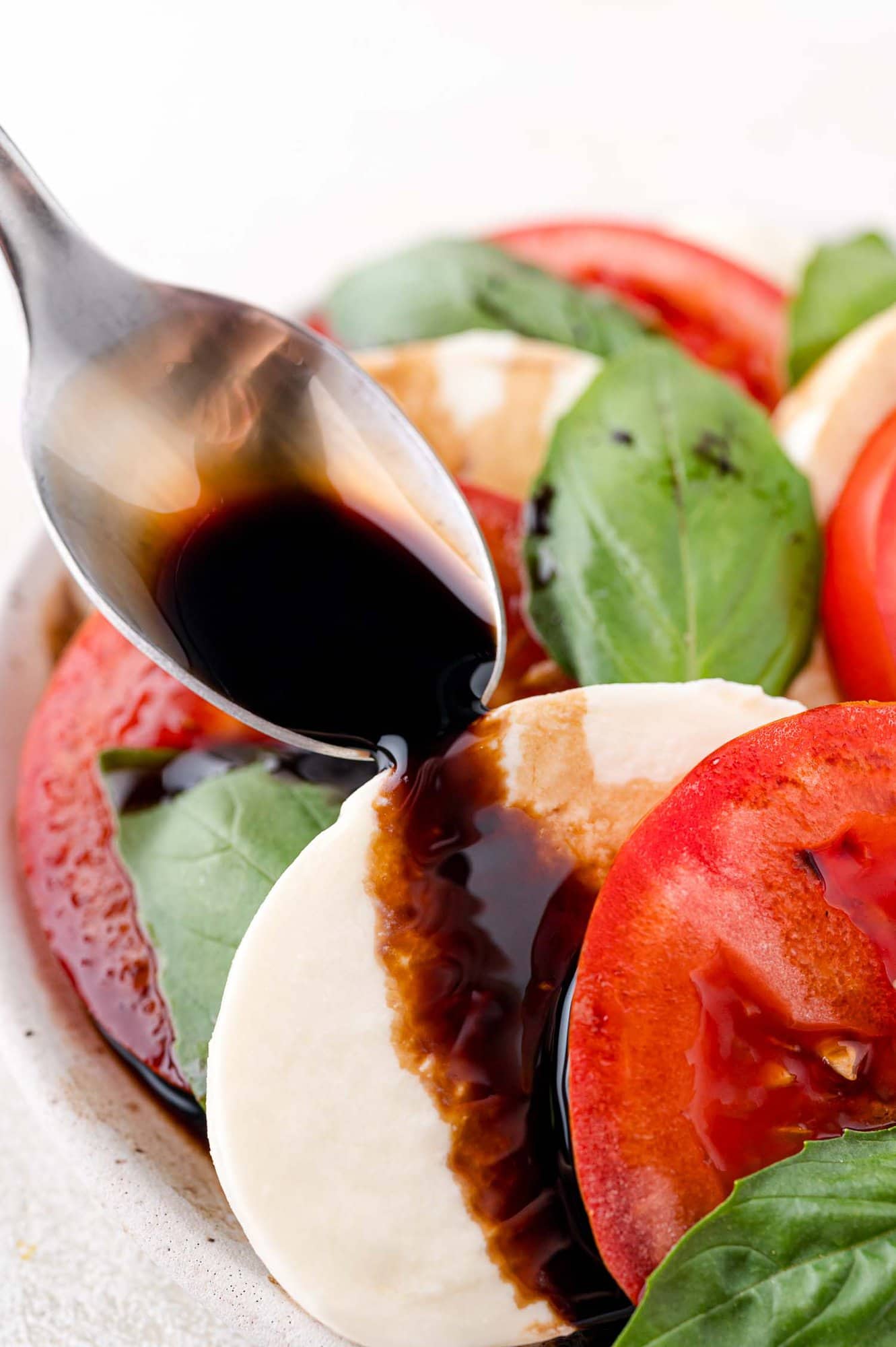 Balsamic glaze being added to a caprese salad.