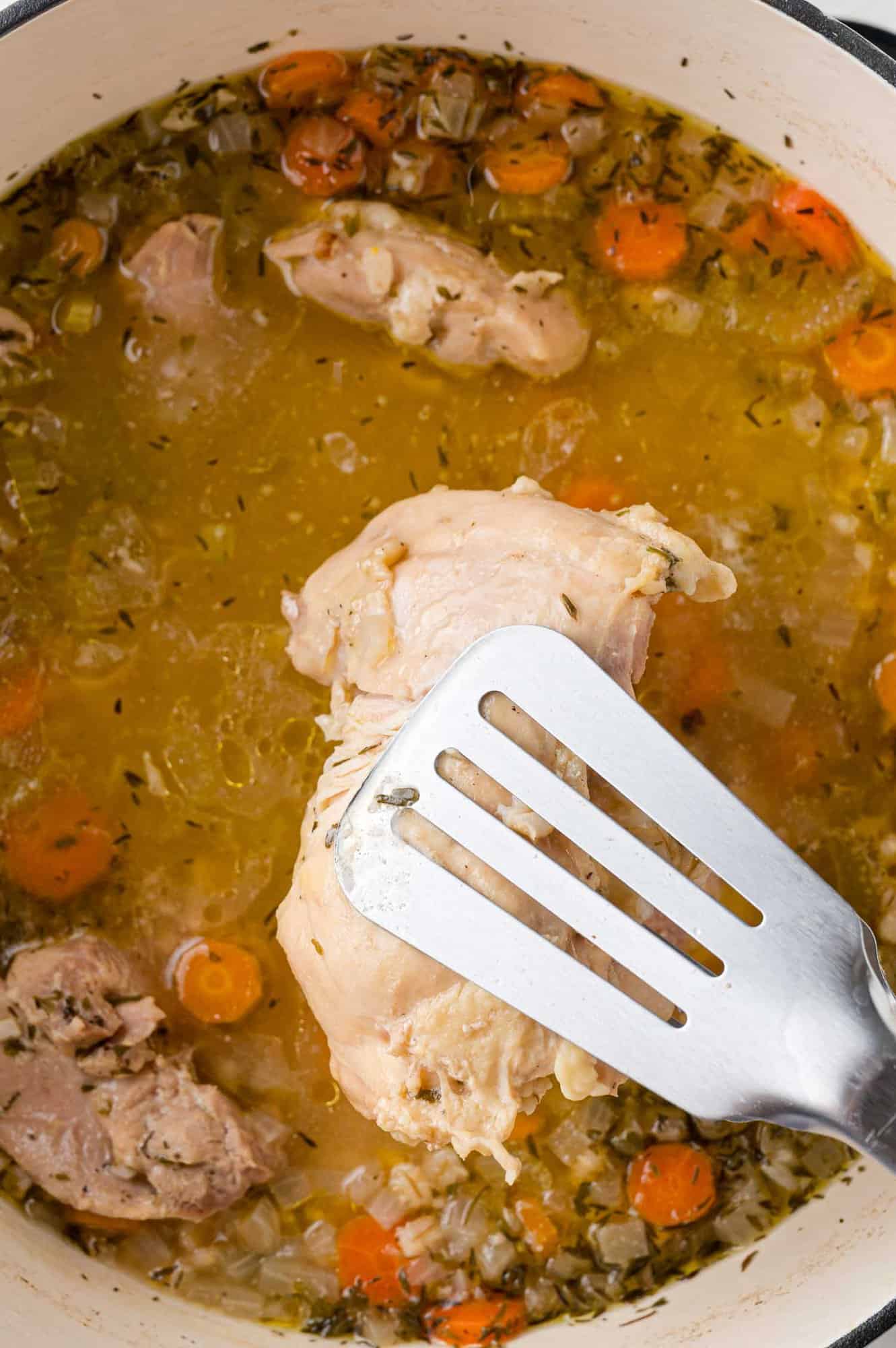 Chicken being removed from soup.