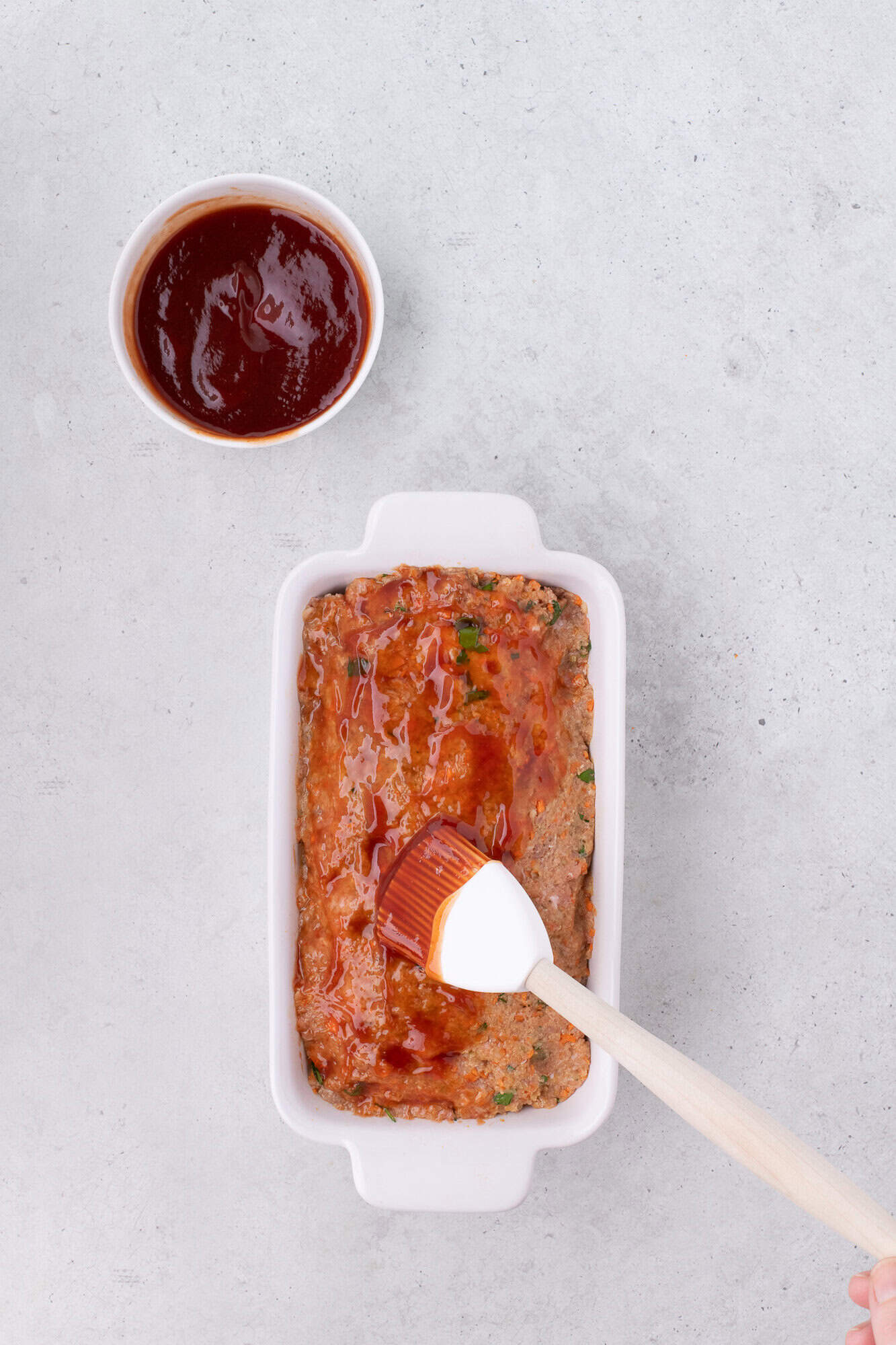 Glaze being spread on meatloaf.