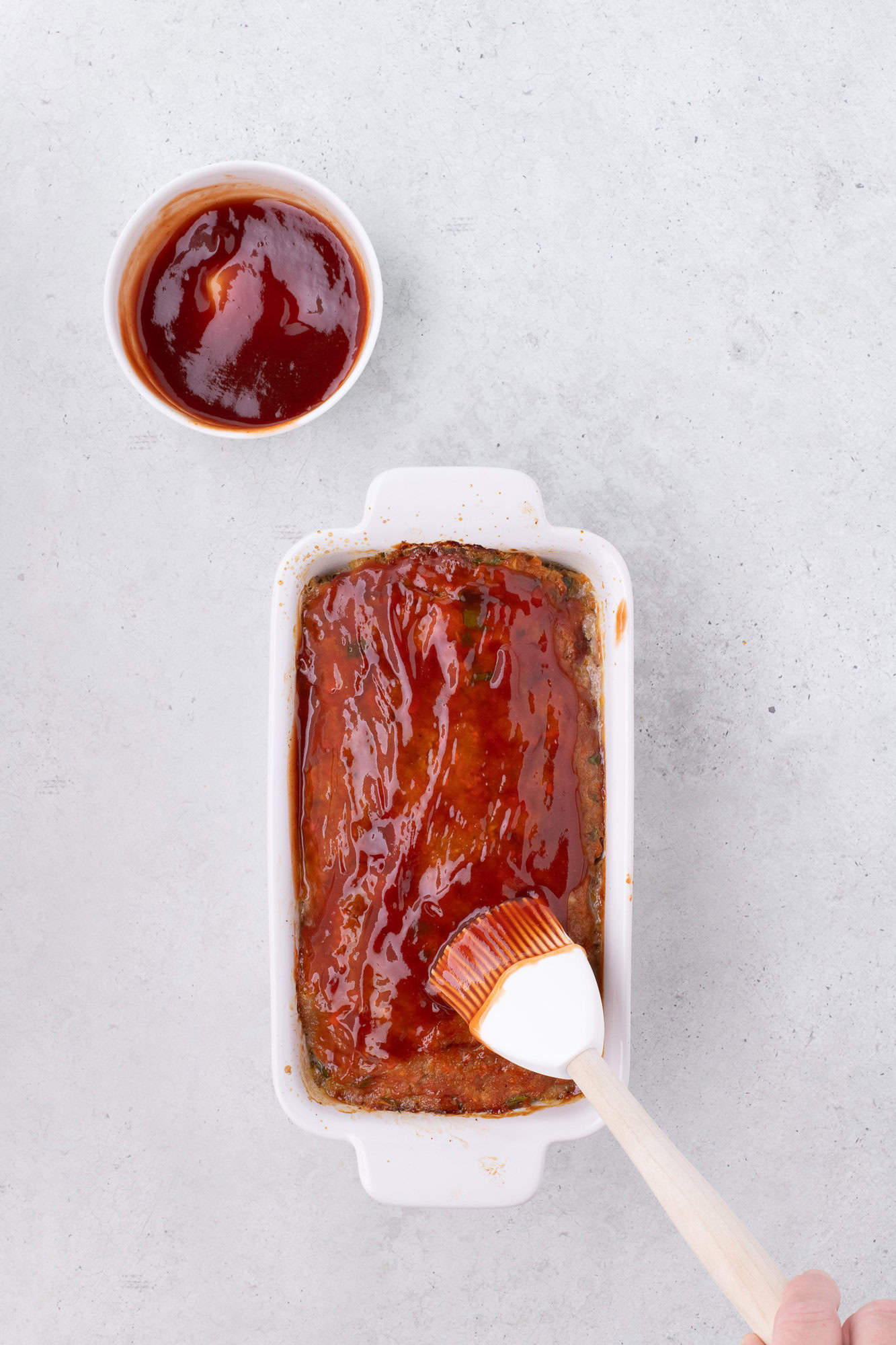 Glaze being spread on meatloaf.