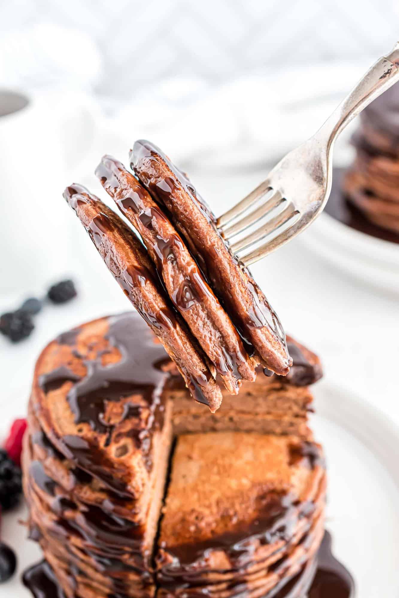 Protein pancakes shown on a fork, with chocolate syrup.