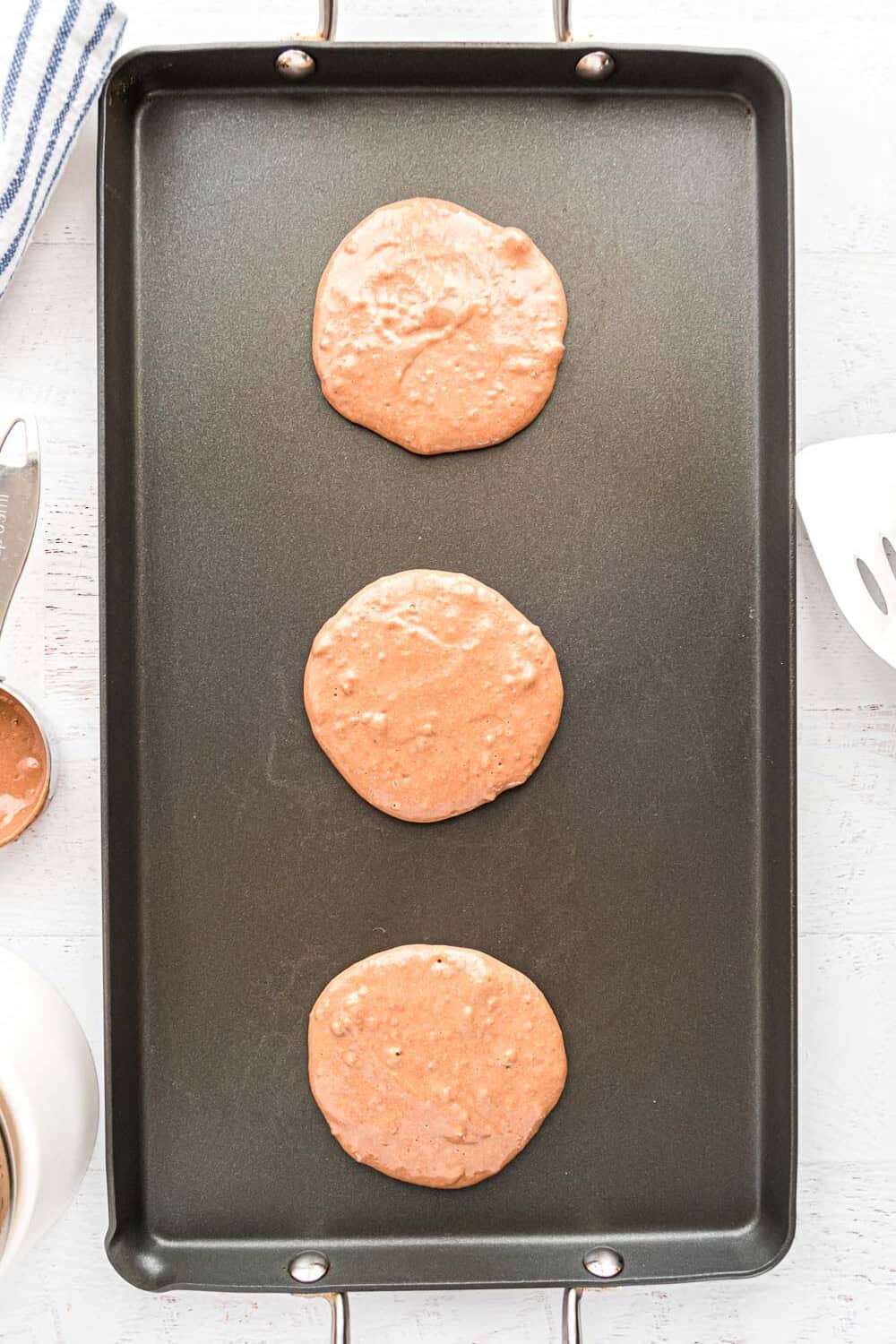 Uncooked pancakes on a griddle.