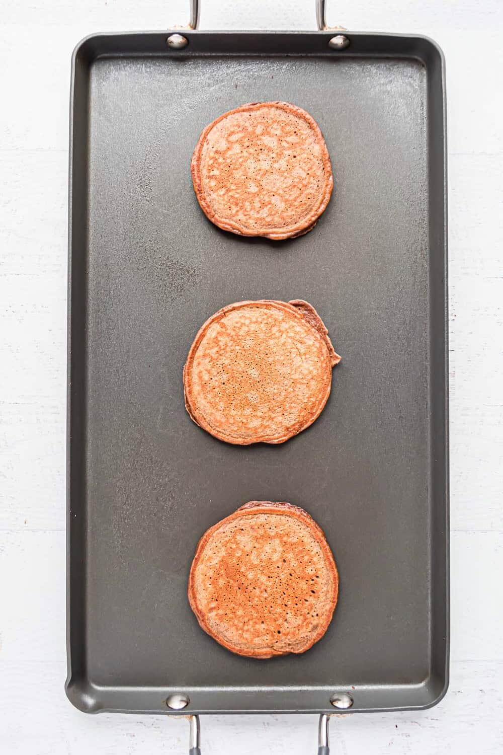 Cooked pancakes on a griddle.