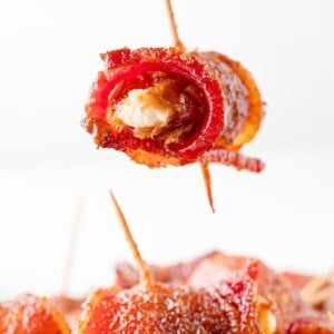 Bacon wrapped date being held over others.
