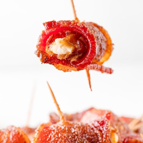 Bacon wrapped date being held over others.