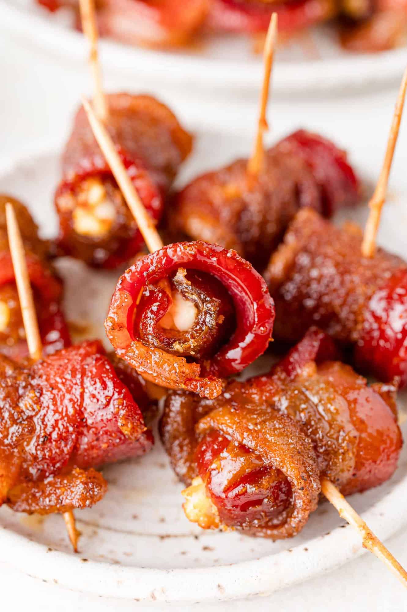 Plate of bacon wrapped dates, stuffed with goat cheese and secured with toothpicks.
