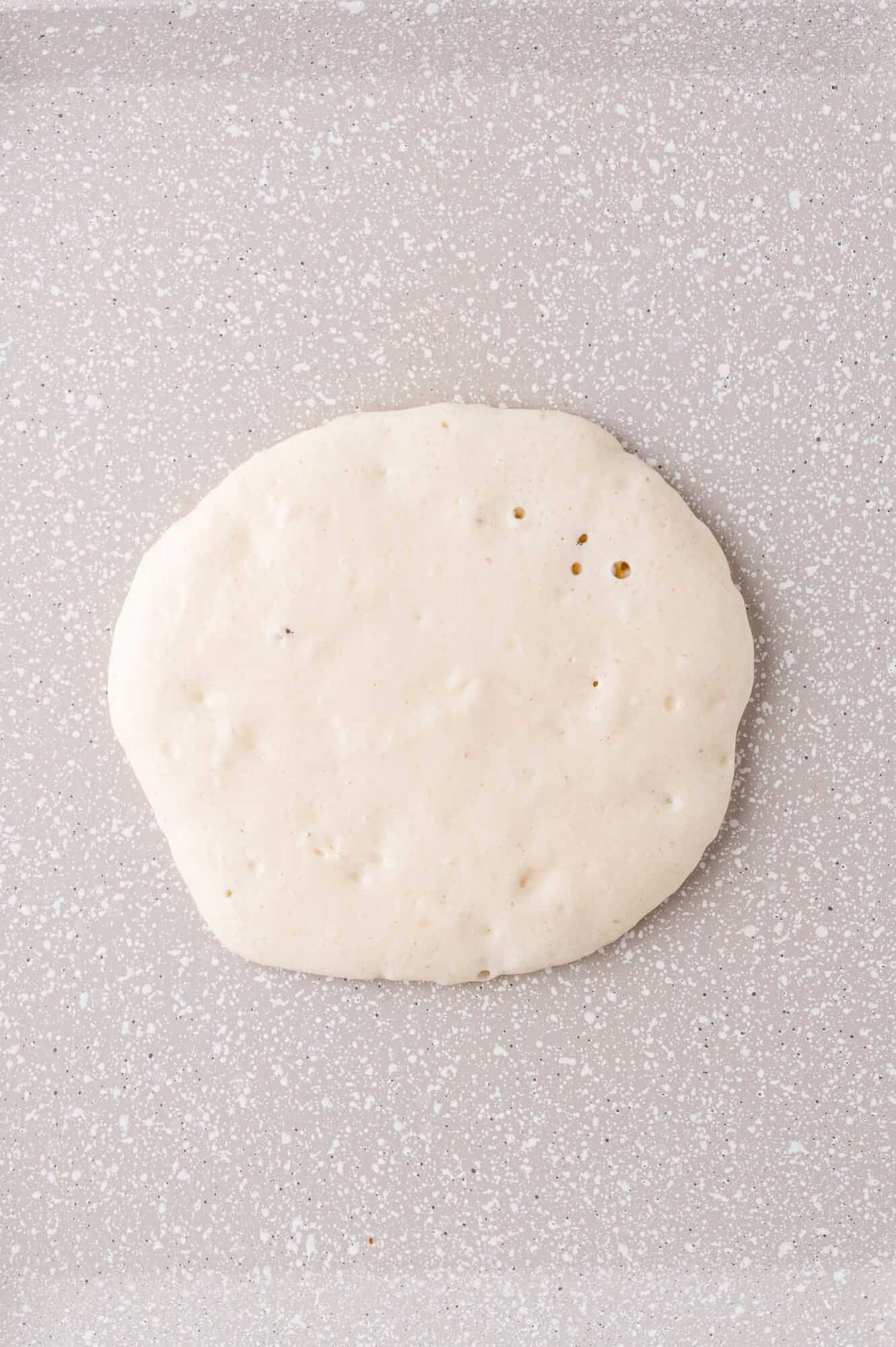 Pancake on griddle, not yet cooked.