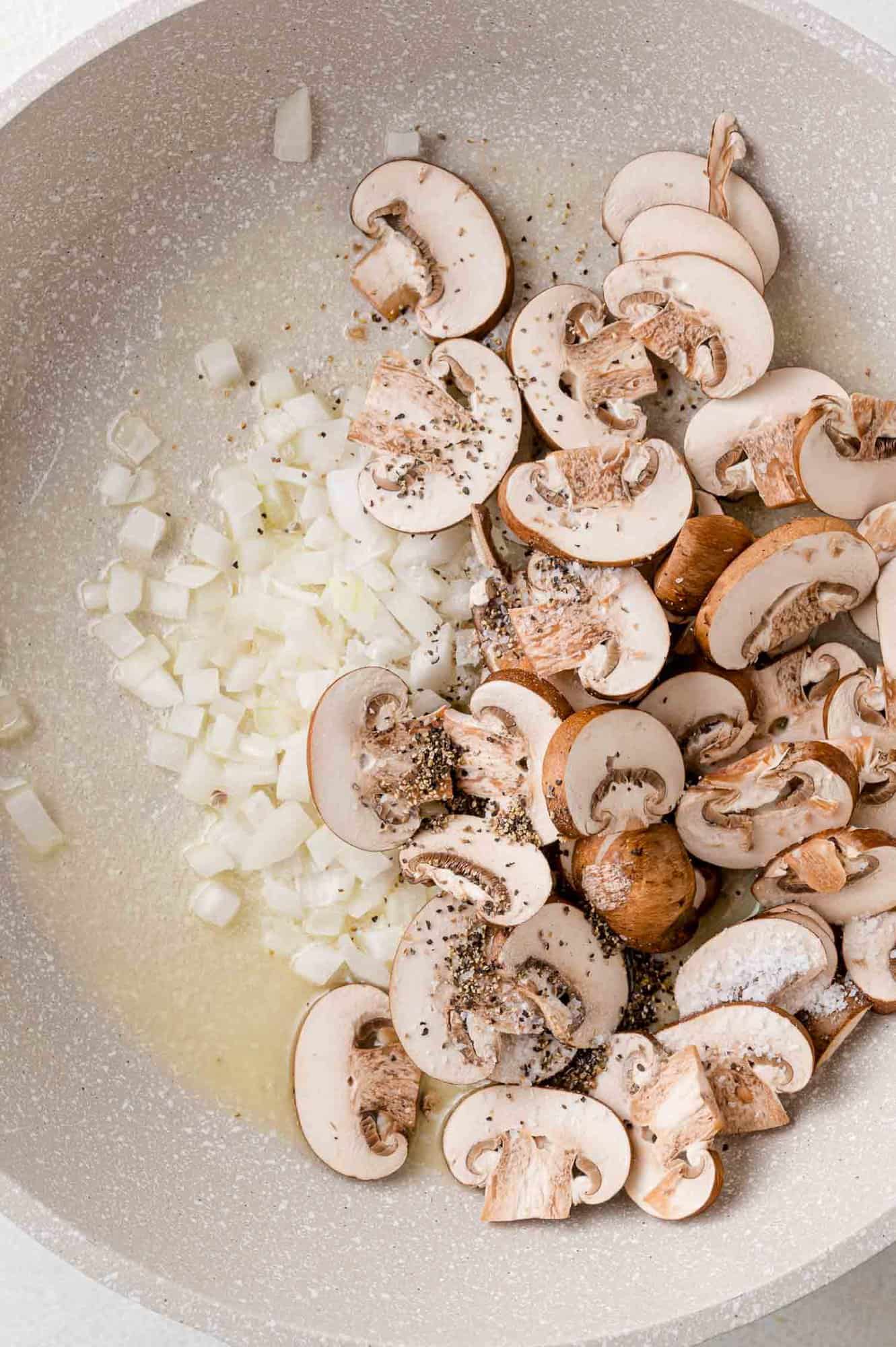 Onions, butter, and mushrooms in a pan, not yet cooked.