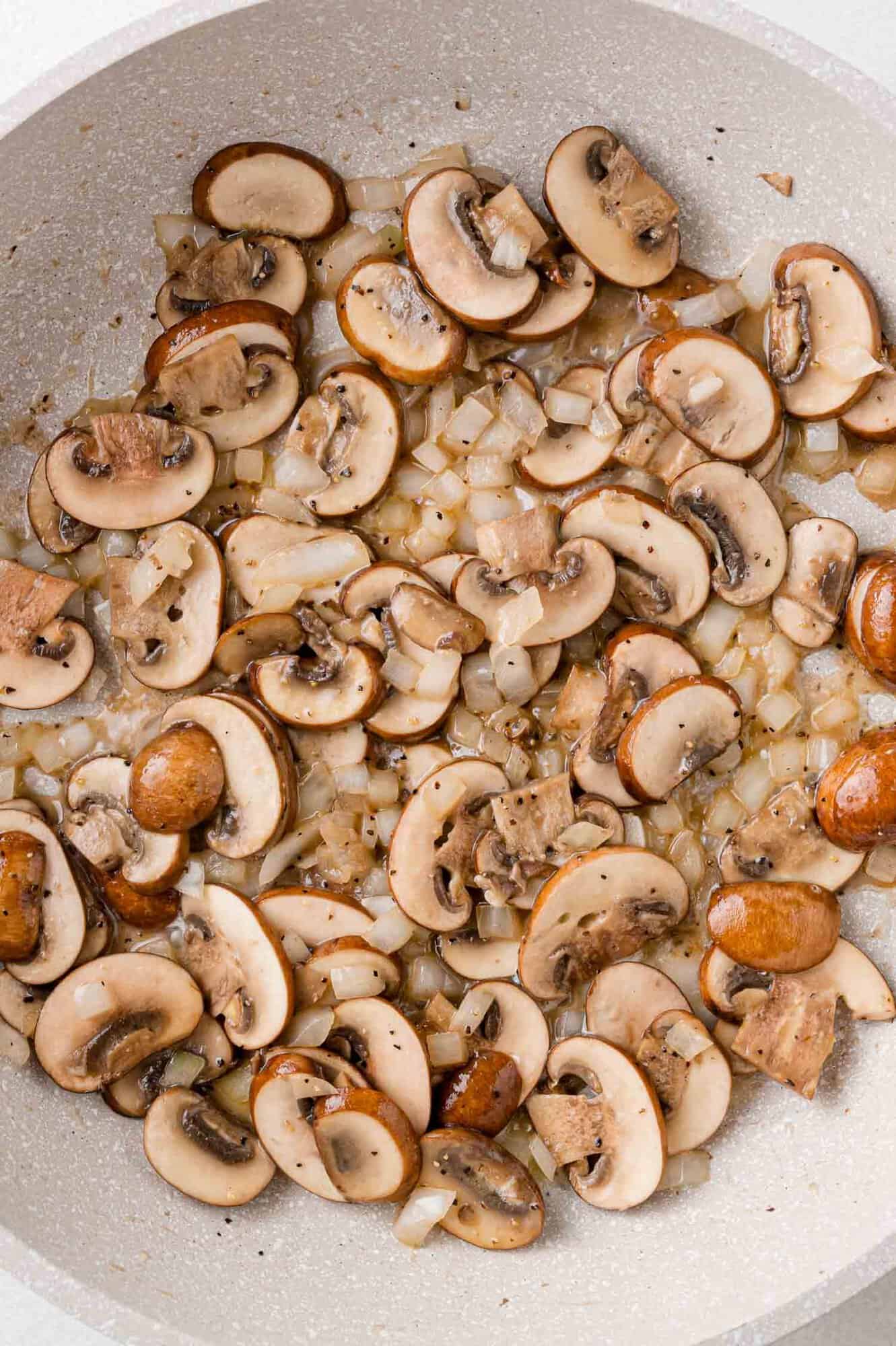 Mushrooms and onions, sautéed in a pan.