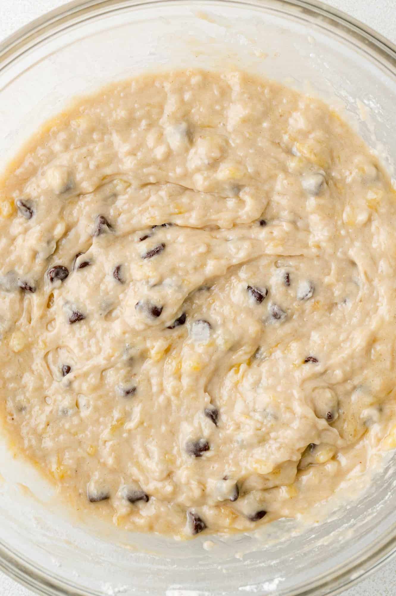 Chocolate chip banana bread batter in a clear glass mixing bowl.