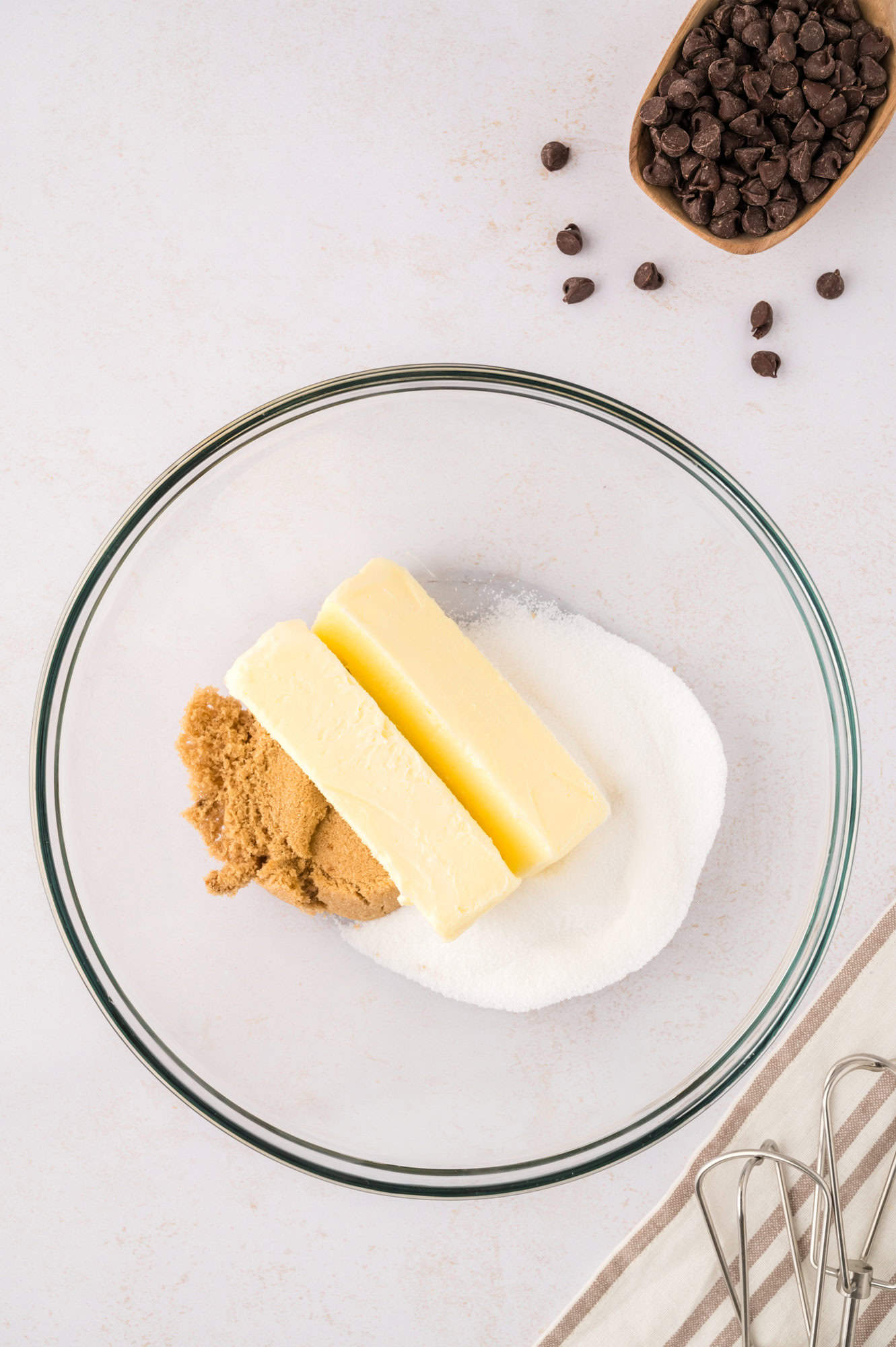 Butter and sugars in a clear glass mixing bowl.