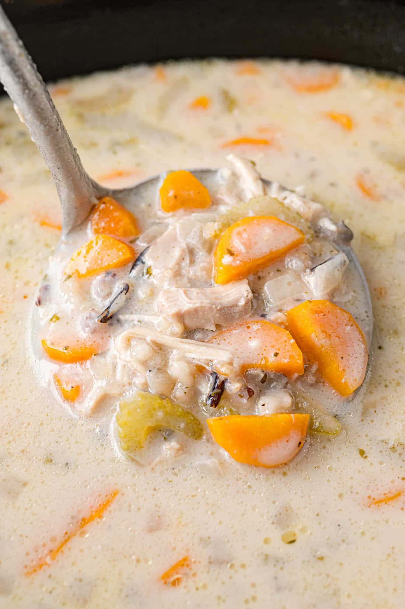 Crockpot chicken wild rice soup in a ladle.