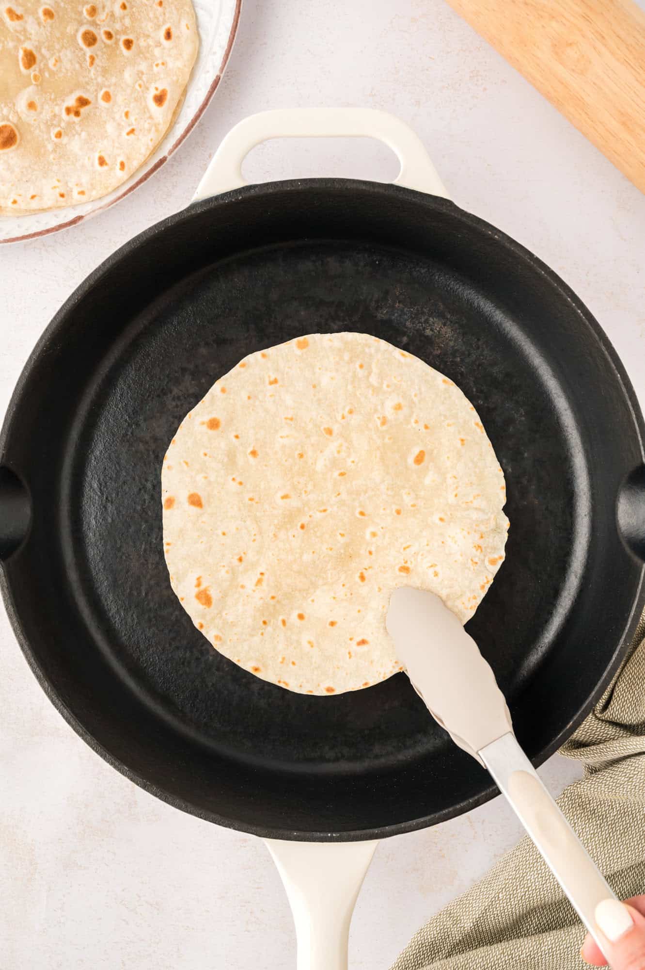Tortilla in a cast iron pan, being flipped over.
