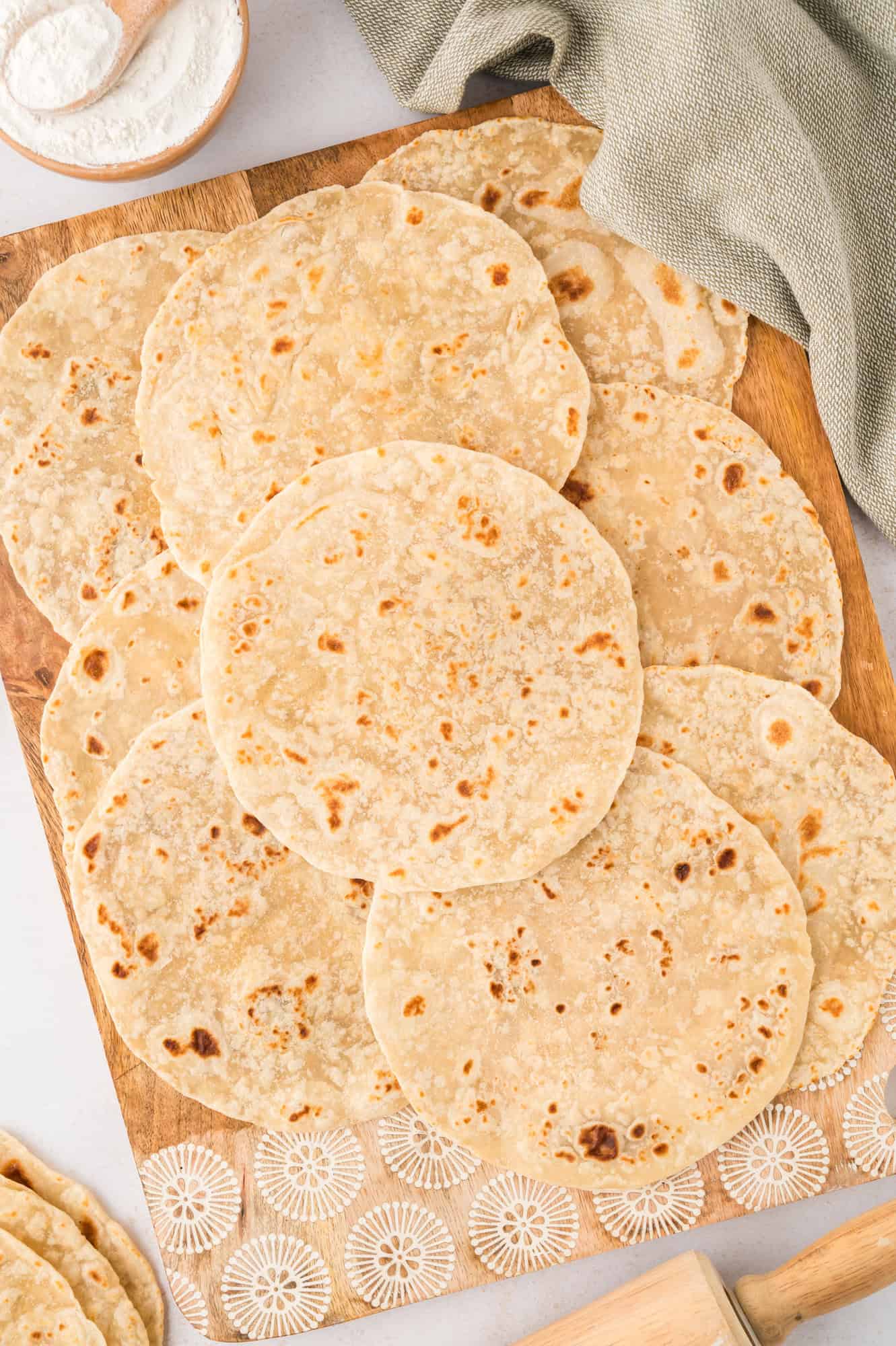 Tortillas laid out on a wooden cutting board.