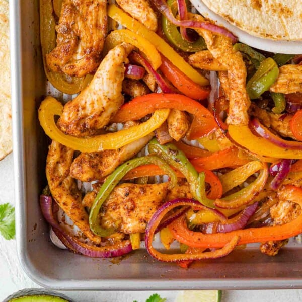 Overhead view of sheet pan fajitas with chicken, peppers, and onions.