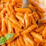 Vodka pasta on penne sauce, garnished with fresh basil leaves.