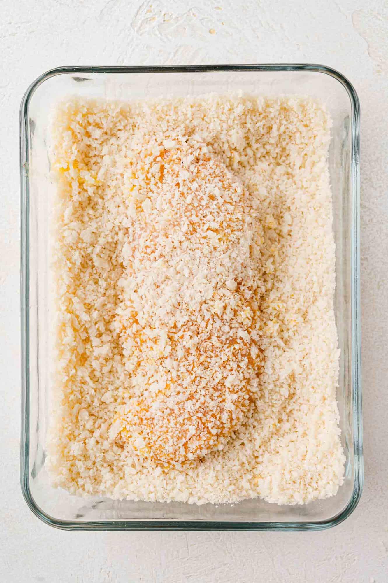 Chicken tender, breaded, still in breading dish.