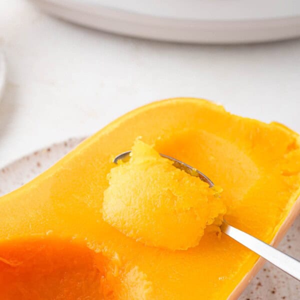 Crockpot butternut squash being scooped from the peel of squash.