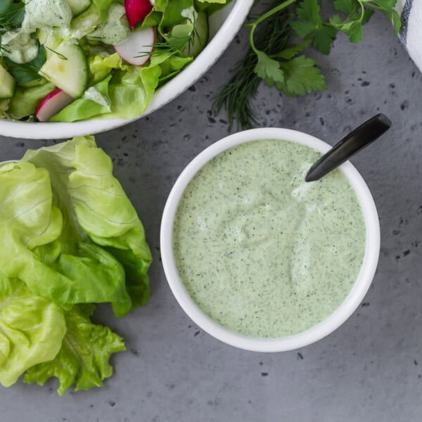 Overhead view of green goddess dressing in a small white bowl.