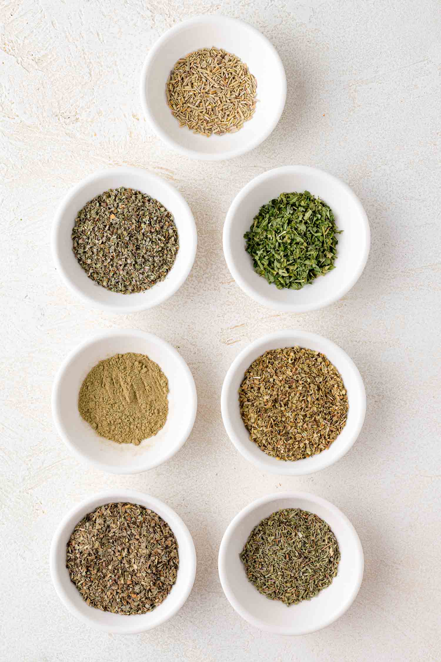 Italian seasoning ingredients in individual small glass bowls.