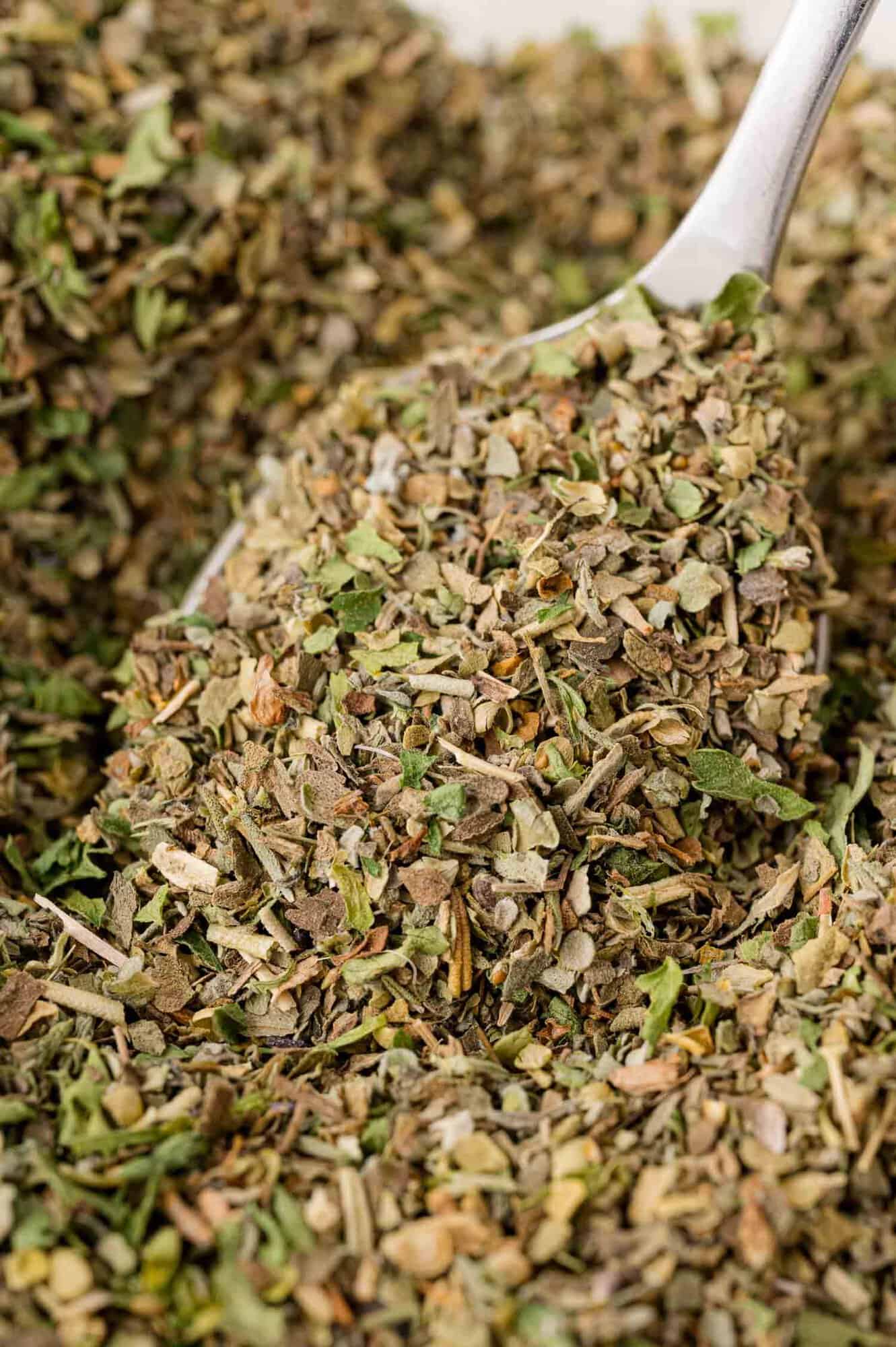 Homemade Italian seasoning, being scooped with a small measuring spoon.