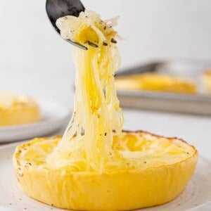 Spaghetti squash being lifted from a ring of cooked squash.