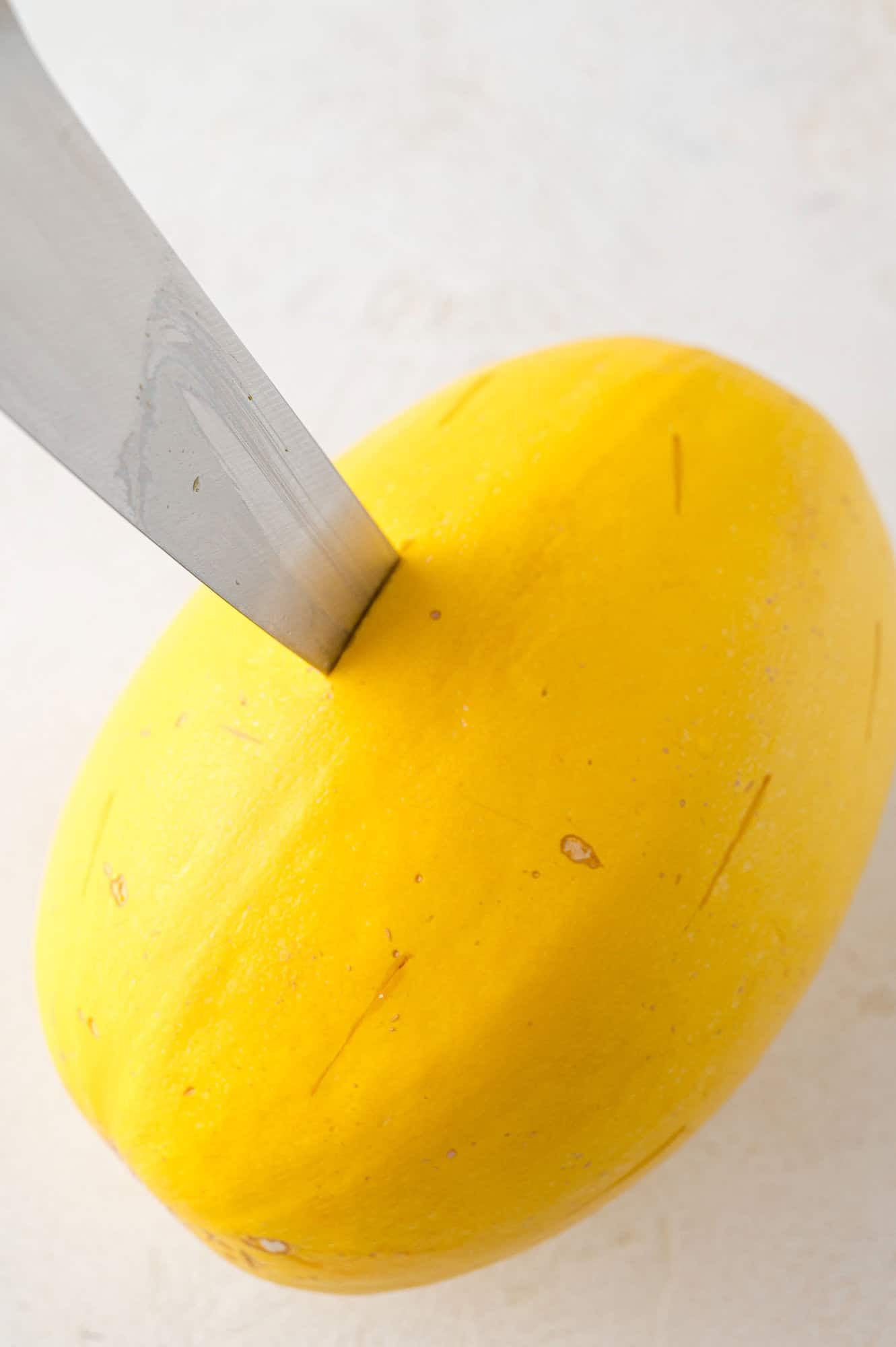 Hole being made in a spaghetti squash with a sharp knife.