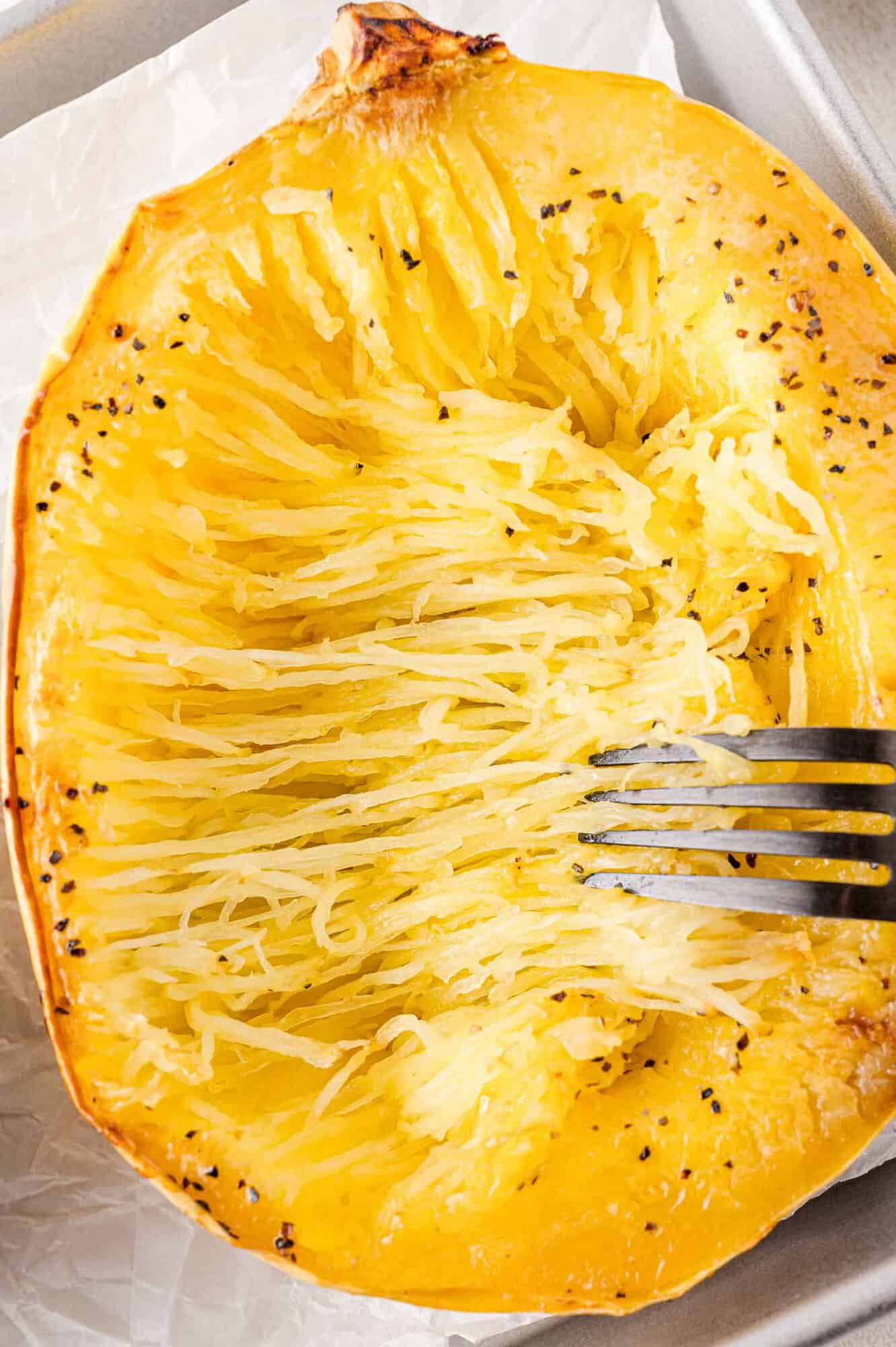 Spaghetti squash being separated into strands using a fork.