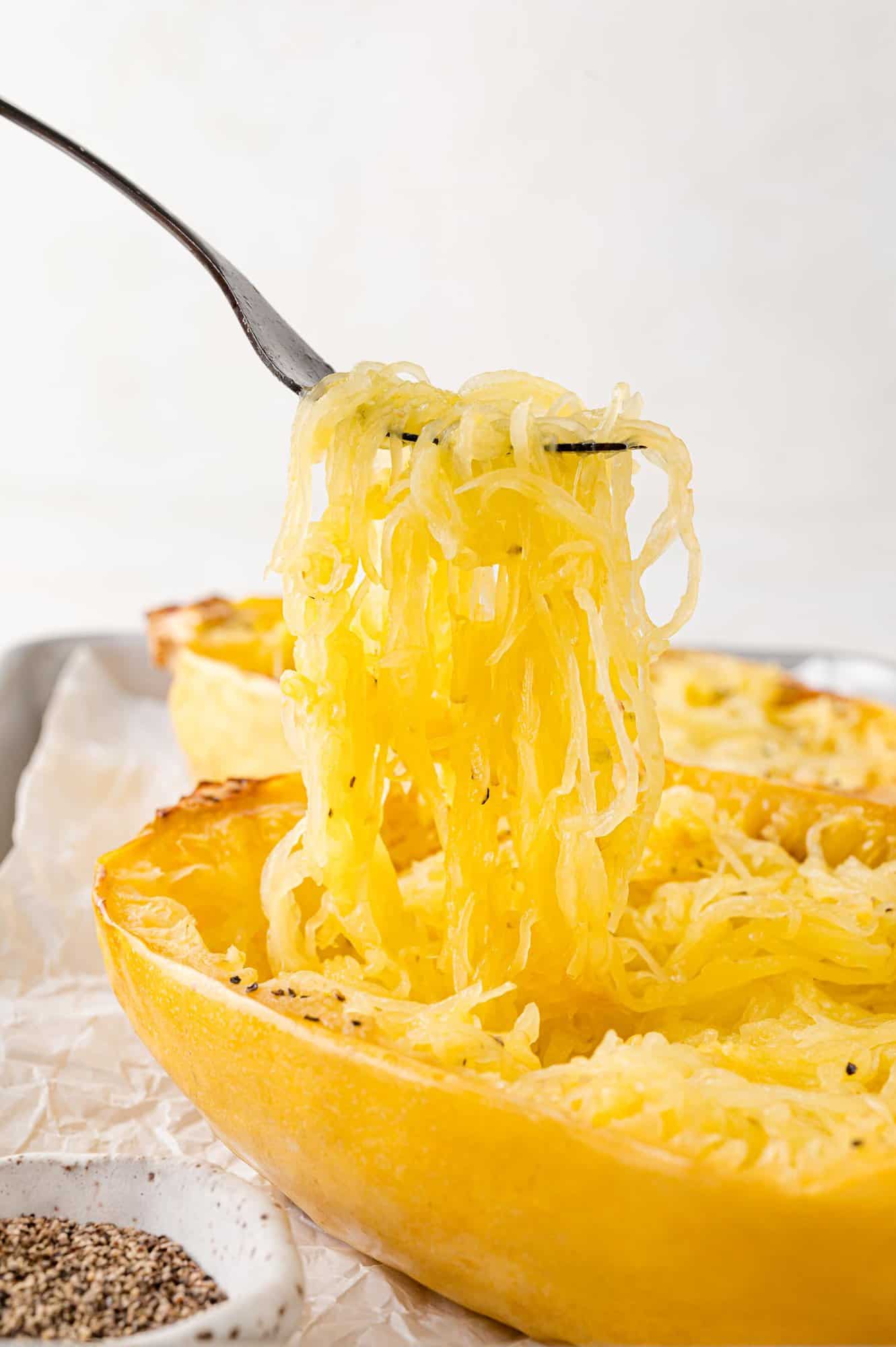 Spaghetti squash being lifted out of baked squash half.