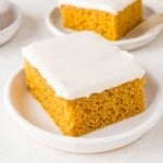 Pumpkin bar with cream cheese frosting on a white plate.
