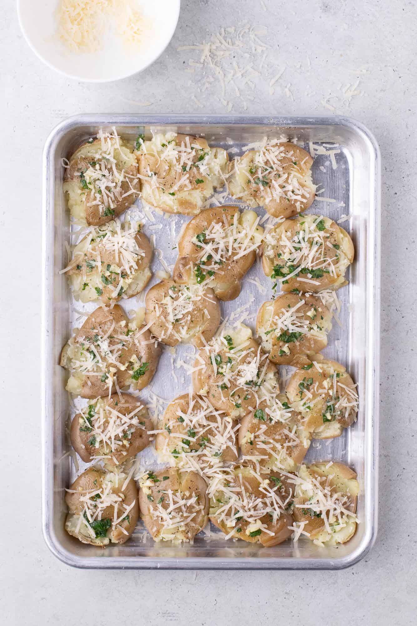 Cheese sprinkled on smashed potatoes.