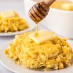 Corn spoon bread scooped onto a plate, with butter on top, being drizzled with honey.