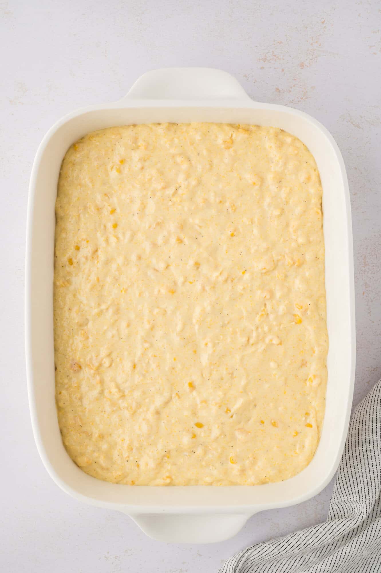 Batter spread into white casserole dish.
