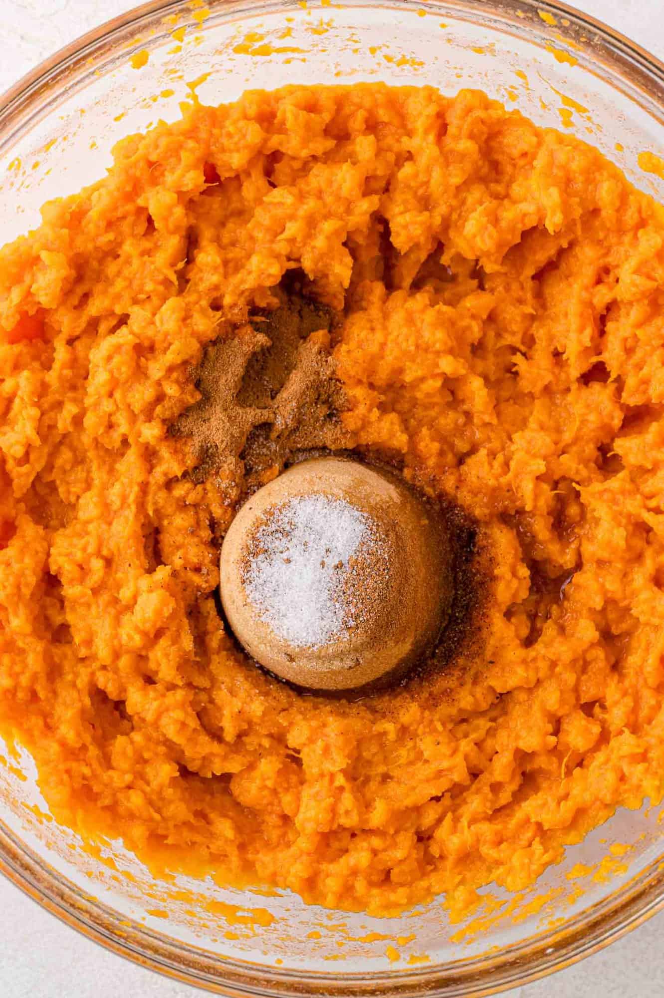 Sugar and other ingredients added to bowl of mashed sweet potatoes, not yet mixed in.
