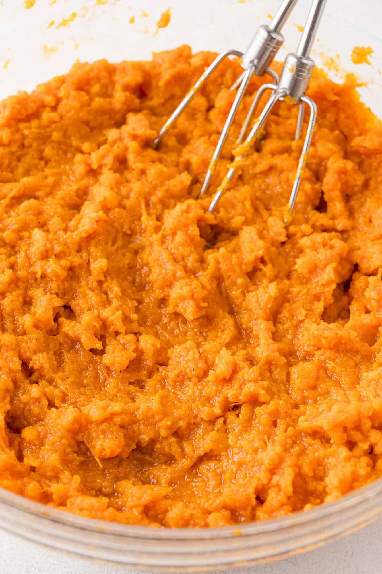 Mashed sweet potatoes mixed with other ingredients, electric mixer beaters still in bowl.