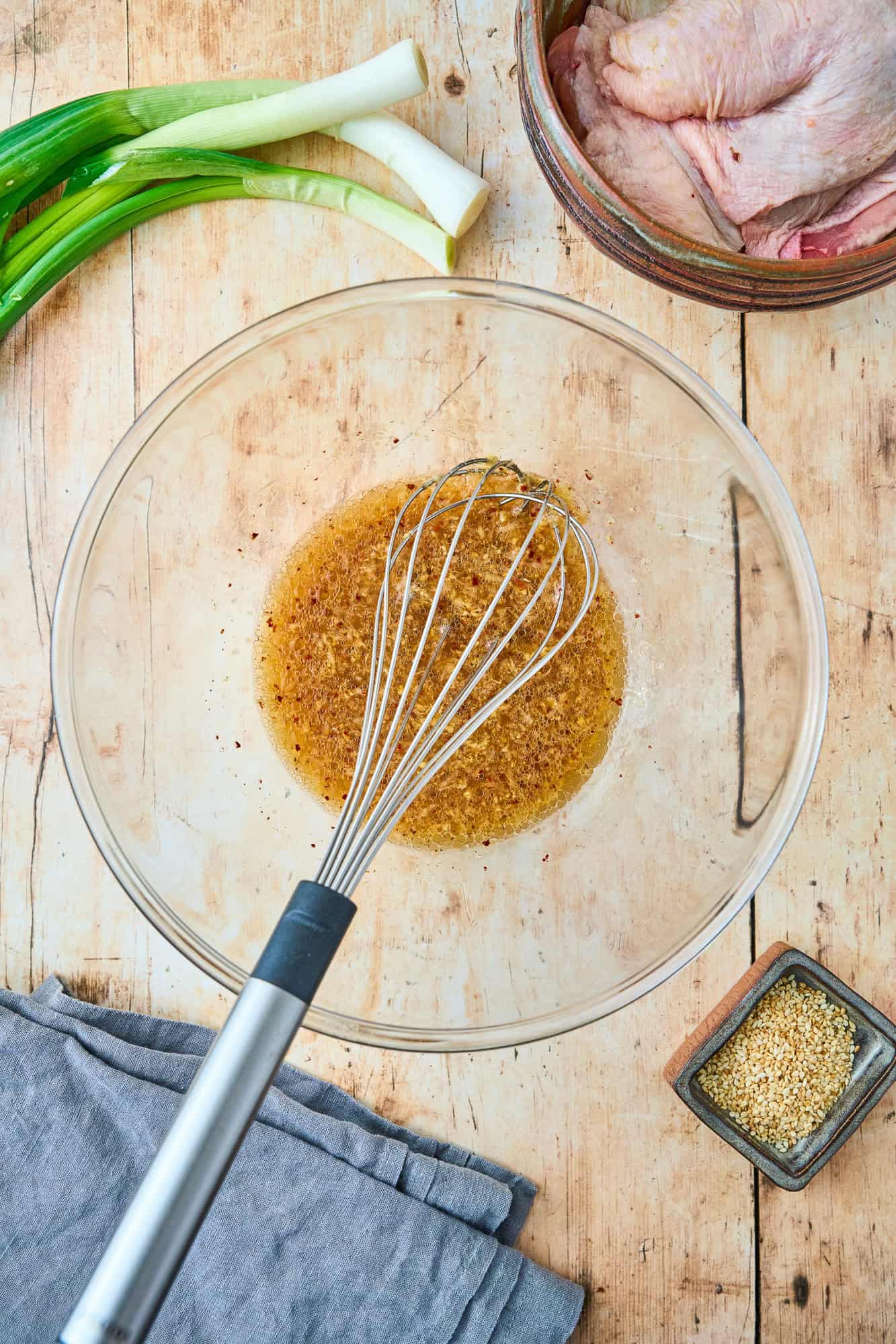 Marinade in clear glass bowl, mixed together with a wire whisk.