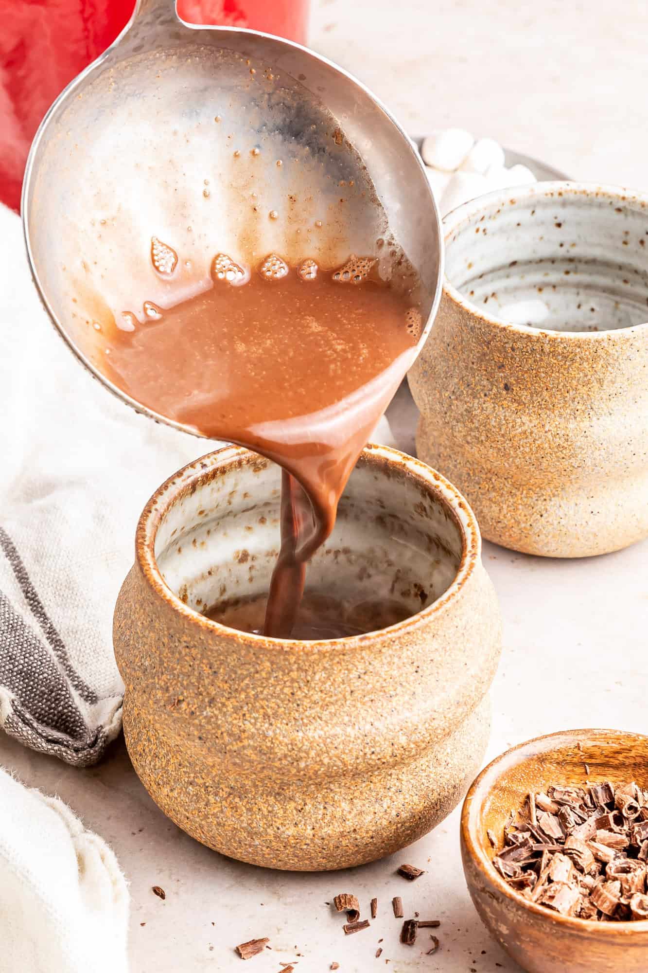 Oat milk hot chocolate being poured into a mug.