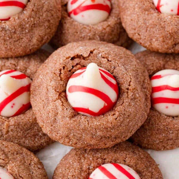Close-up of chocolate cookies topped with white chocolate kisses, decorated with red swirls.