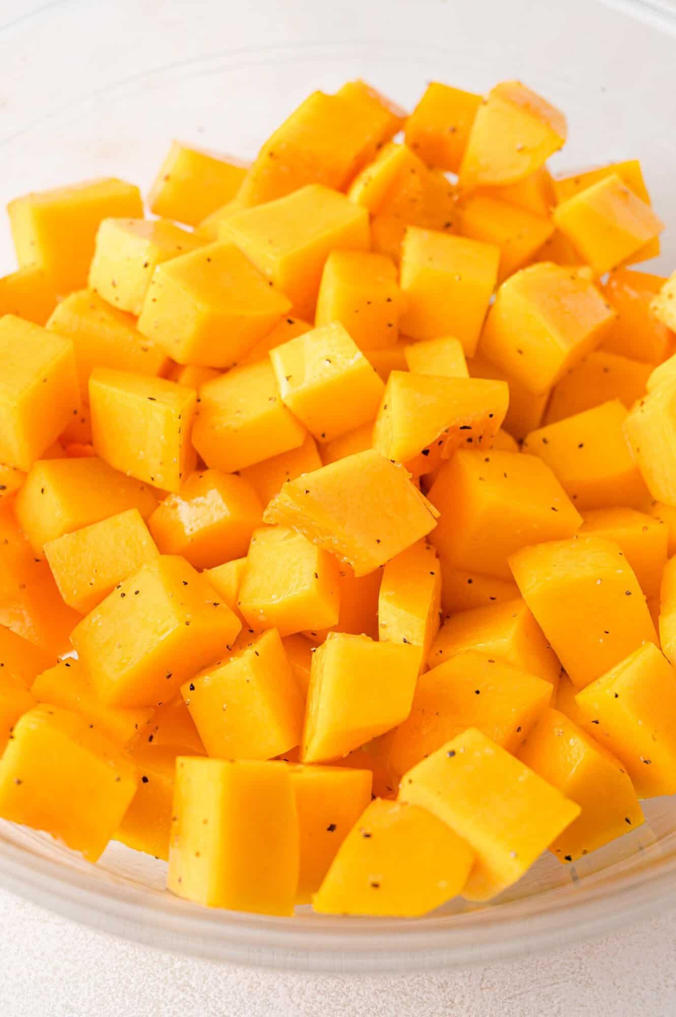 A bowl filled with cubed pieces of fresh, bright orange squash.