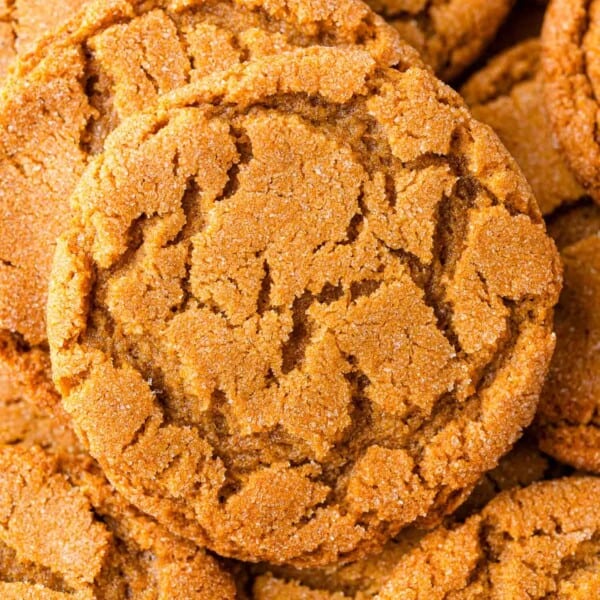 Close-up of a stack of crinkled gingersnap cookies, with a golden-brown, sugar-coated surface.