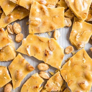 Close-up of broken pieces of peanut brittle scattered on a surface.