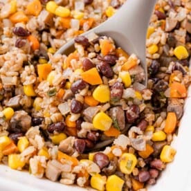 A close-up of a spoonful of mixed vegetables, rice, and beans.