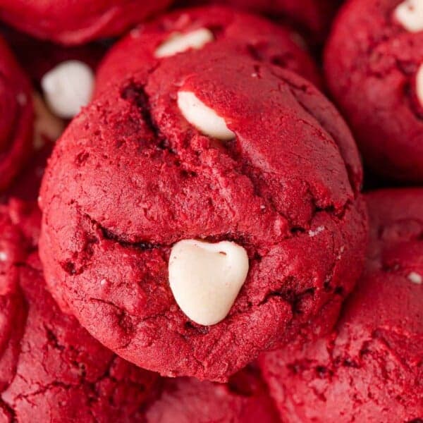 Close-up of a stack of red velvet cookies with white chocolate chips embedded in them.