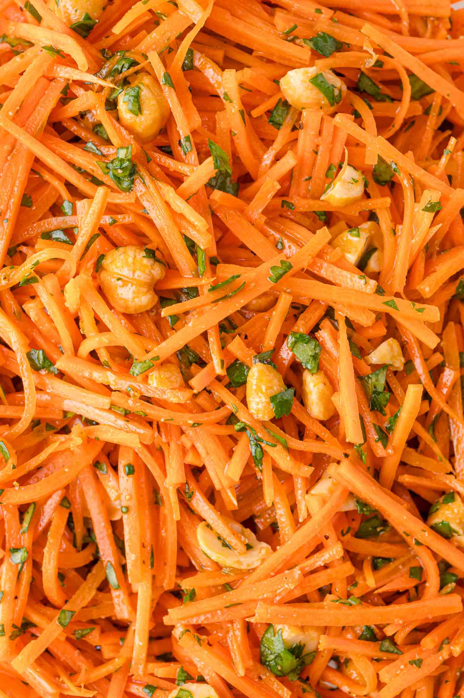 Close-up of a carrot salad with shredded carrots, chopped cilantro, and cashews.