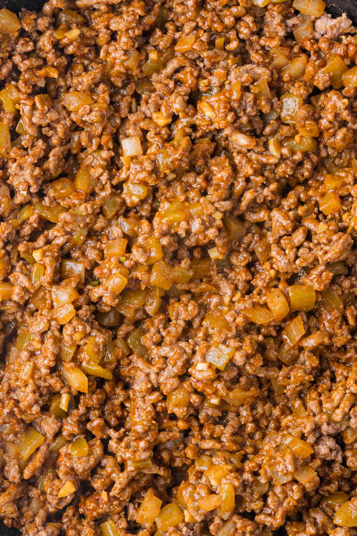 Close-up of cooked ground meat mixed with chopped onions and spices.