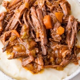 Shredded braised beef with carrots and spices served on a bed of mashed potatoes.